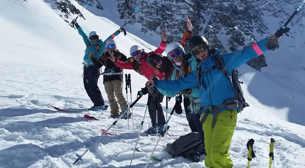 A group of skiers celebrating on a snowy slope at Silverton Mountain