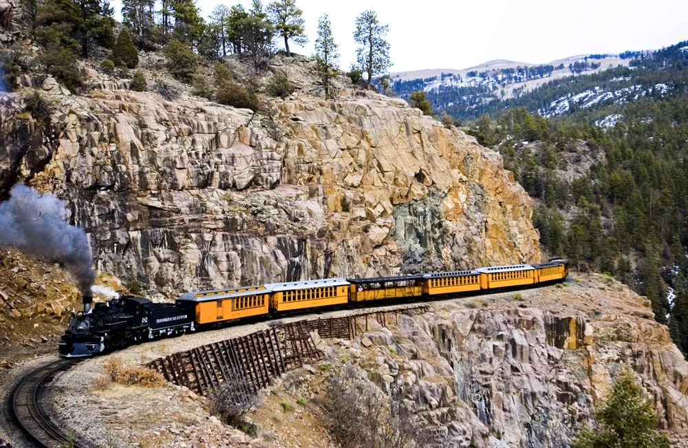 The Durango and Silverton Narrow Gauge steam train rounding a cliffside trestle